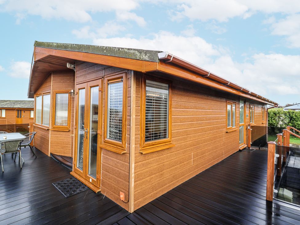 A wooden cabin with a deck and chairs at Ocean View in Ilfracombe