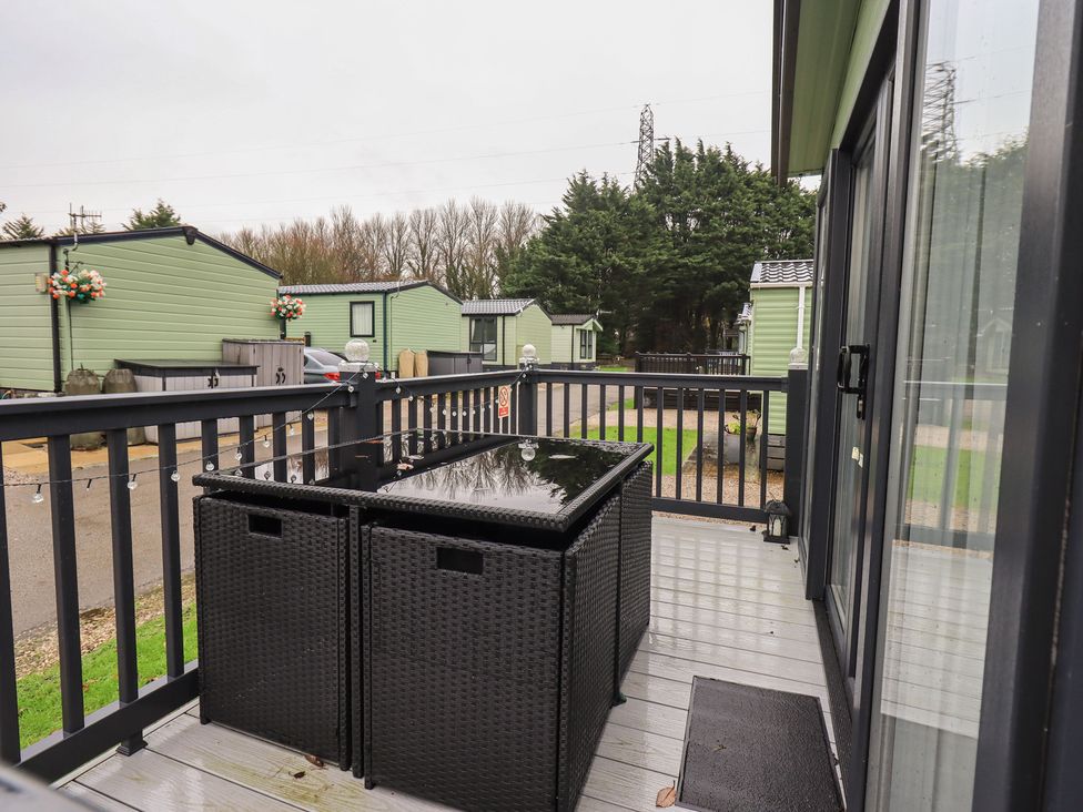 A deck with outdoor table and green caravans in view at Caravan