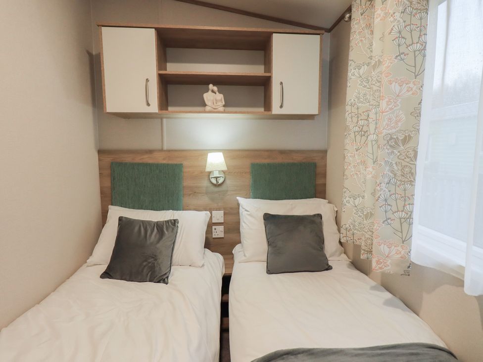 A bedroom with two single beds and a shelf at Caravan
