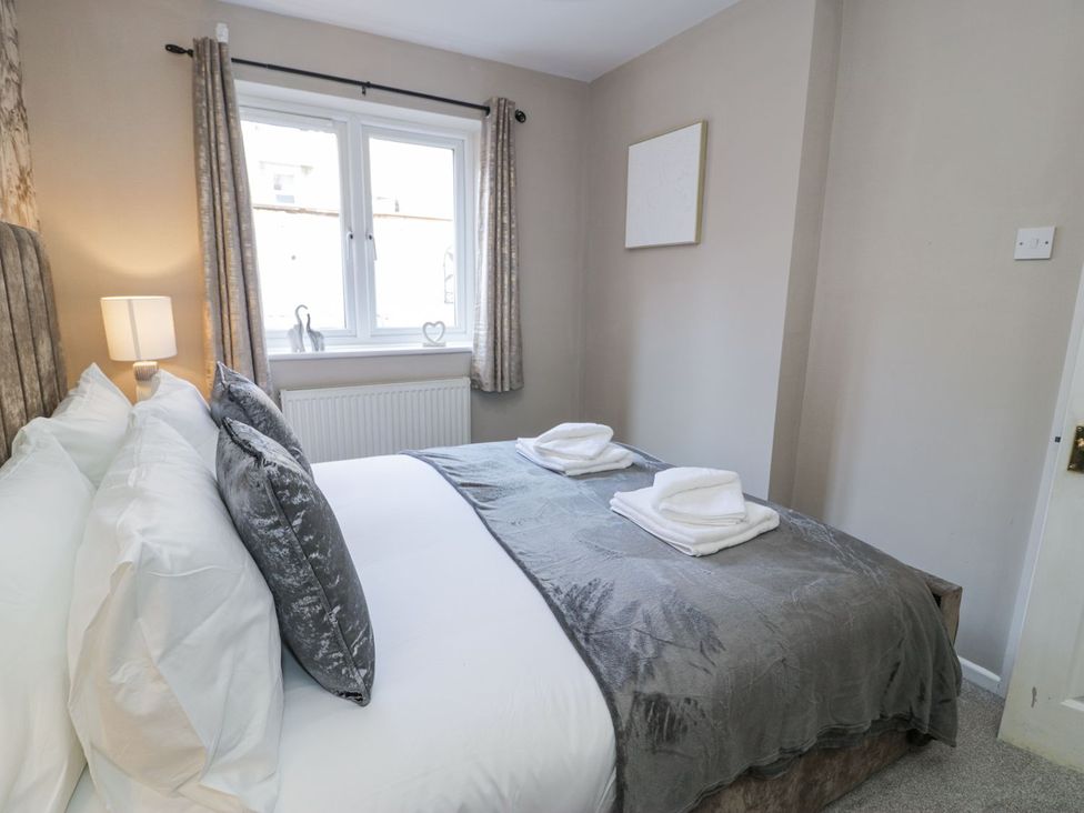 A bedroom with a bed, lamp, and window at Canning Lodge in Colwyn Bay