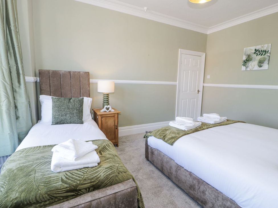 A bedroom with twin beds and bedside table at Canning Lodge Colwyn Bay
