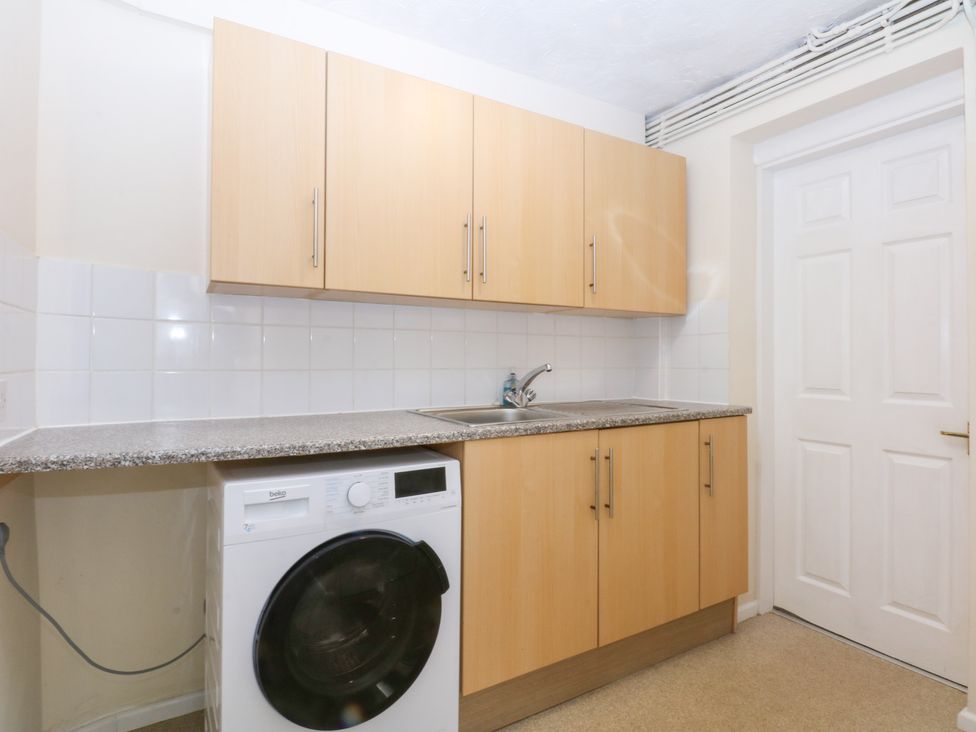 A kitchen with a washing machine and cabinets at Canning Lodge in Colwyn Bay