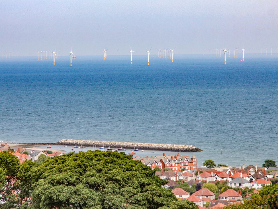 A view of wind turbines over the ocean with houses along the beach at Canning Lodge in Colwyn Bay
