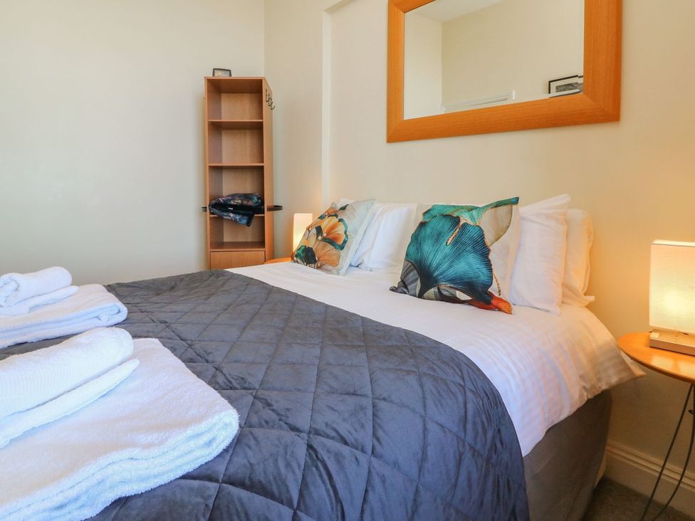 A bedroom with a bed and shelves at Val's Seaview in Ilfracombe