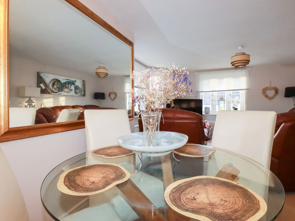 A dining room with a glass table and decorative flowers at 18 Pagoda Drive St. Austell