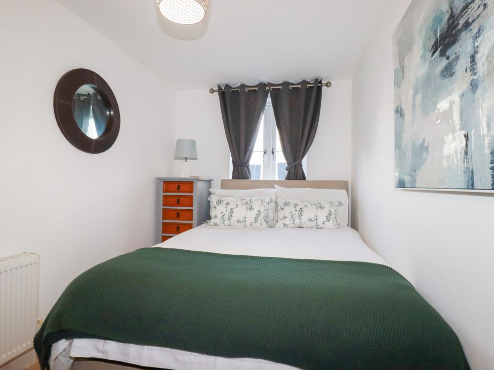 A bedroom with a bed and wooden cabinet at 18 Pagoda Drive St. Austell