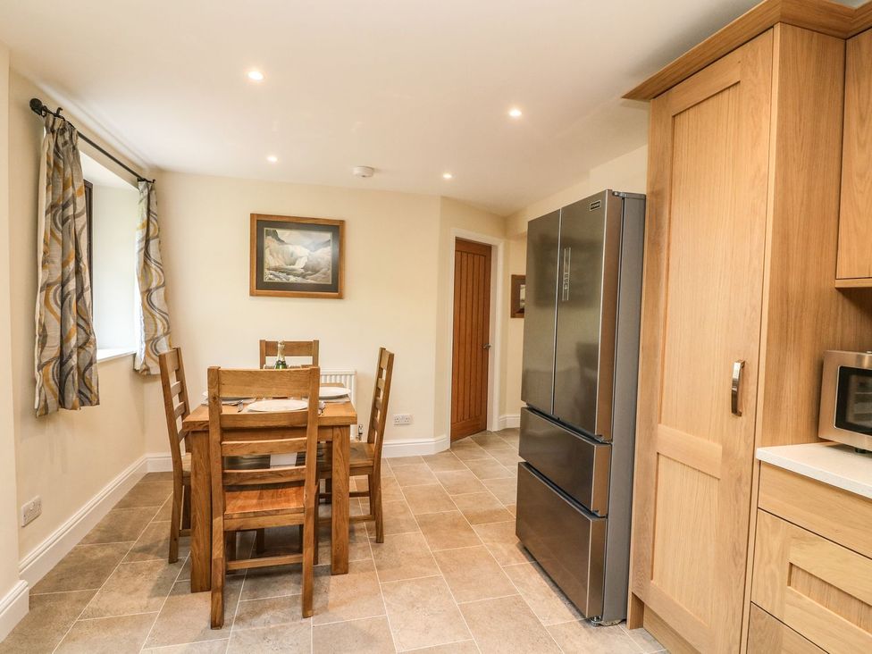 A kitchen with a dining table and refrigerator at The Coach House in Carnforth
