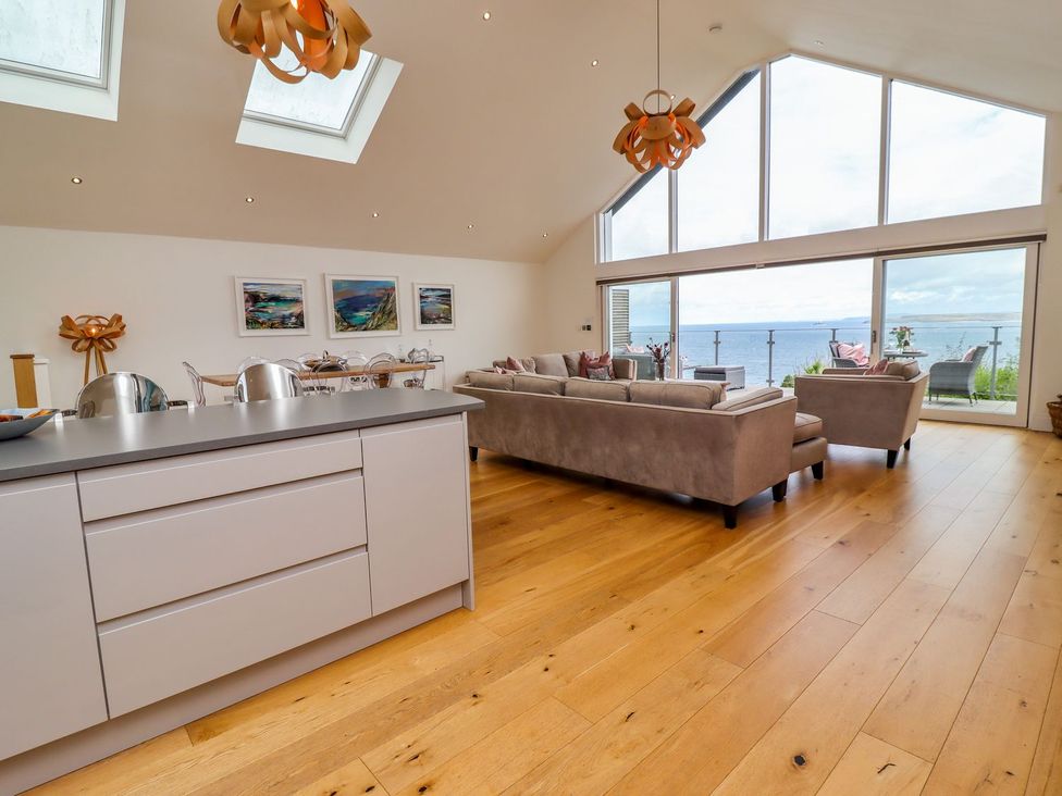 A living room with a kitchen island and large windows at 2 Remera St. Ives