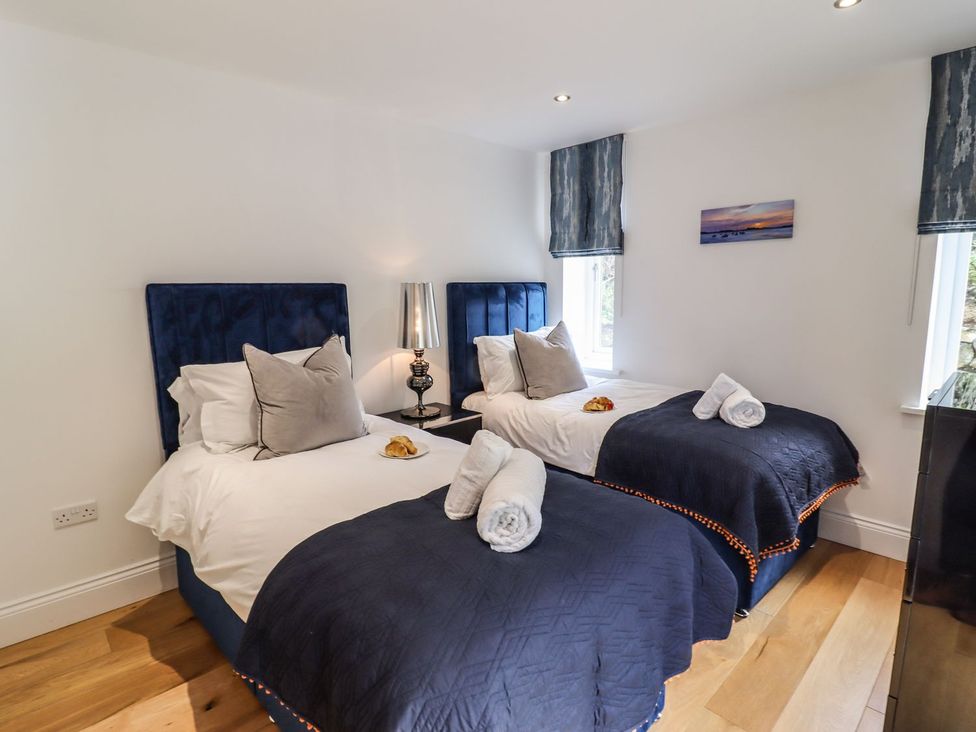 A bedroom with two beds and a bedside lamp at 2 Remera St. Ives