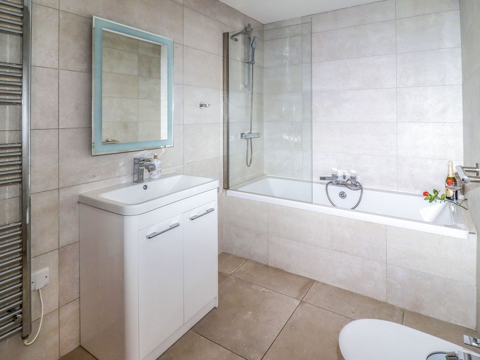 A bathroom with a bath, sink, toilet and mirror at 2 Remera in St. Ives