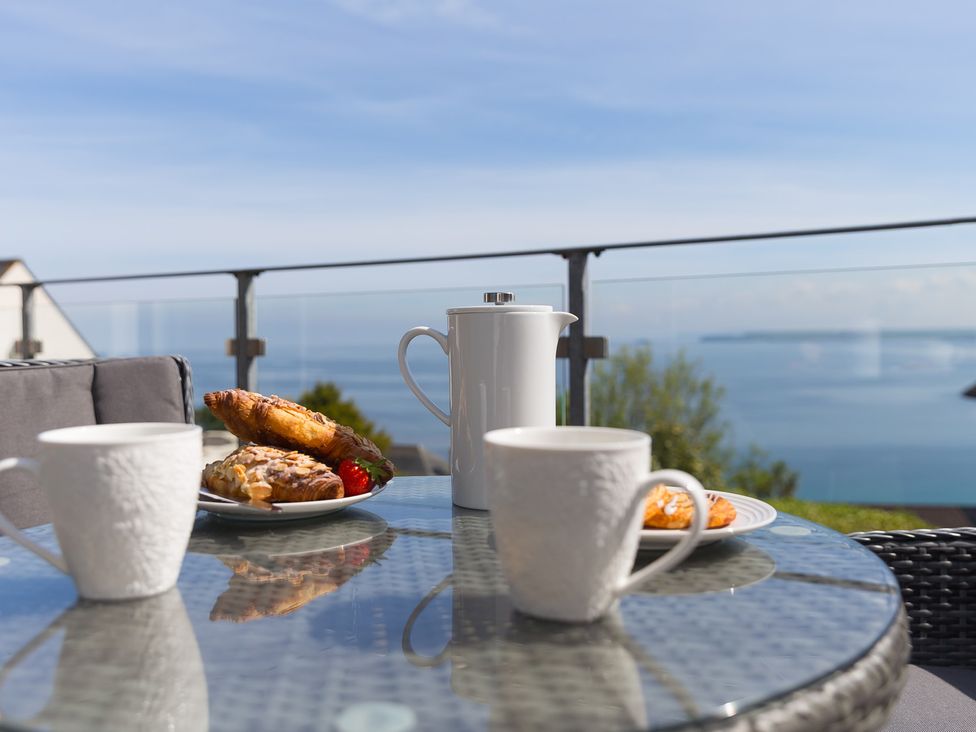 A table with cups and a teapot on a balcony at 2 Remera St Ives