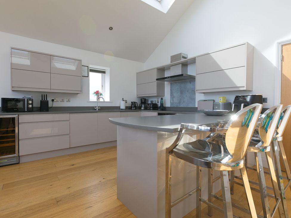 A kitchen with modern appliances and bar stools at 2 Remera St Ives