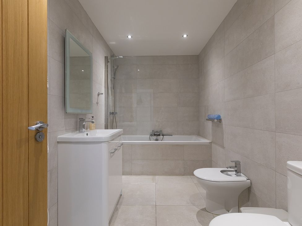 A bathroom with a bathtub, toilet, sink, and mirror at 2 Remera in St Ives