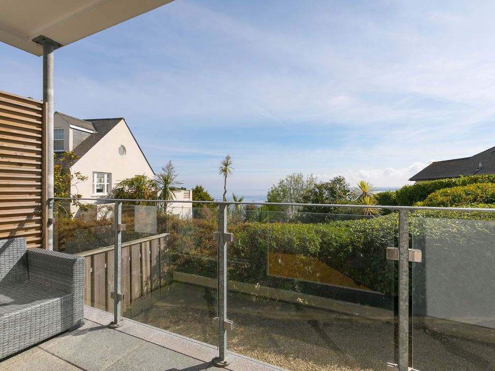 A balcony with a glass railing and a couch at 2 Remera in St Ives