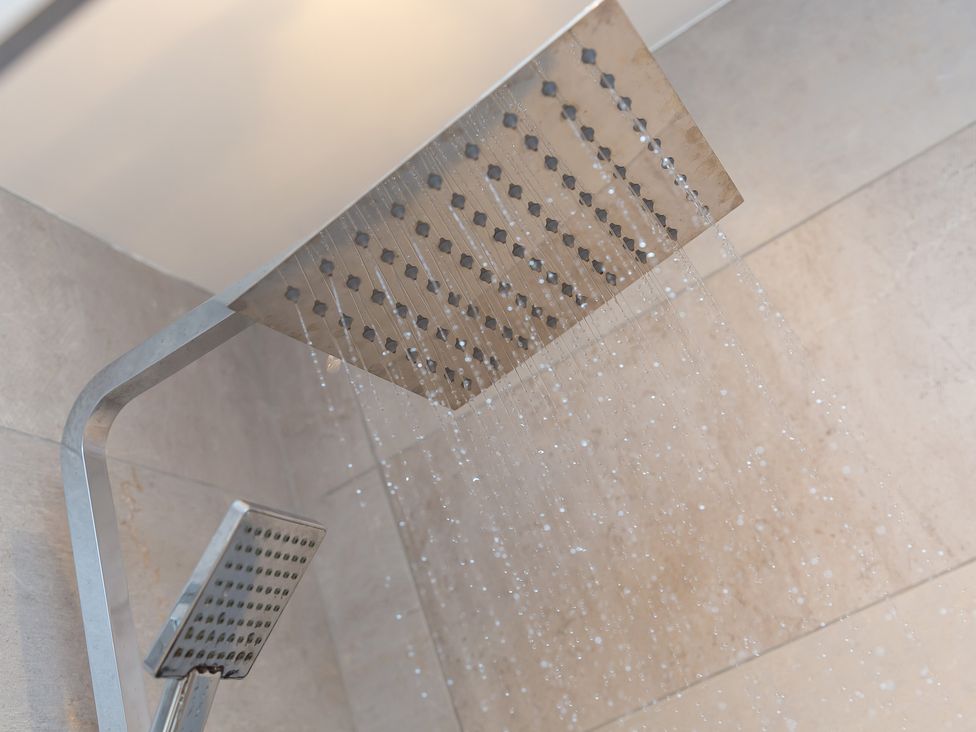 A shower with overhead and handheld shower heads at 2 Remera St Ives