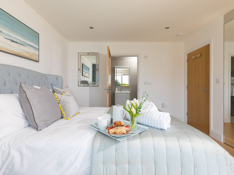A bedroom with a bed and tray of food and drink at 2 Remera in St Ives