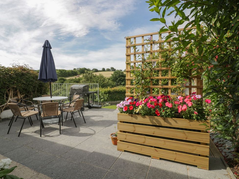 A garden with a table and chairs under an umbrella at Orchard View in St. Austell