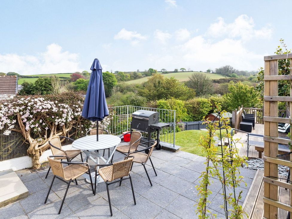 A garden with a table and chairs and a barbecue grill at Orchard View in St. Austell
