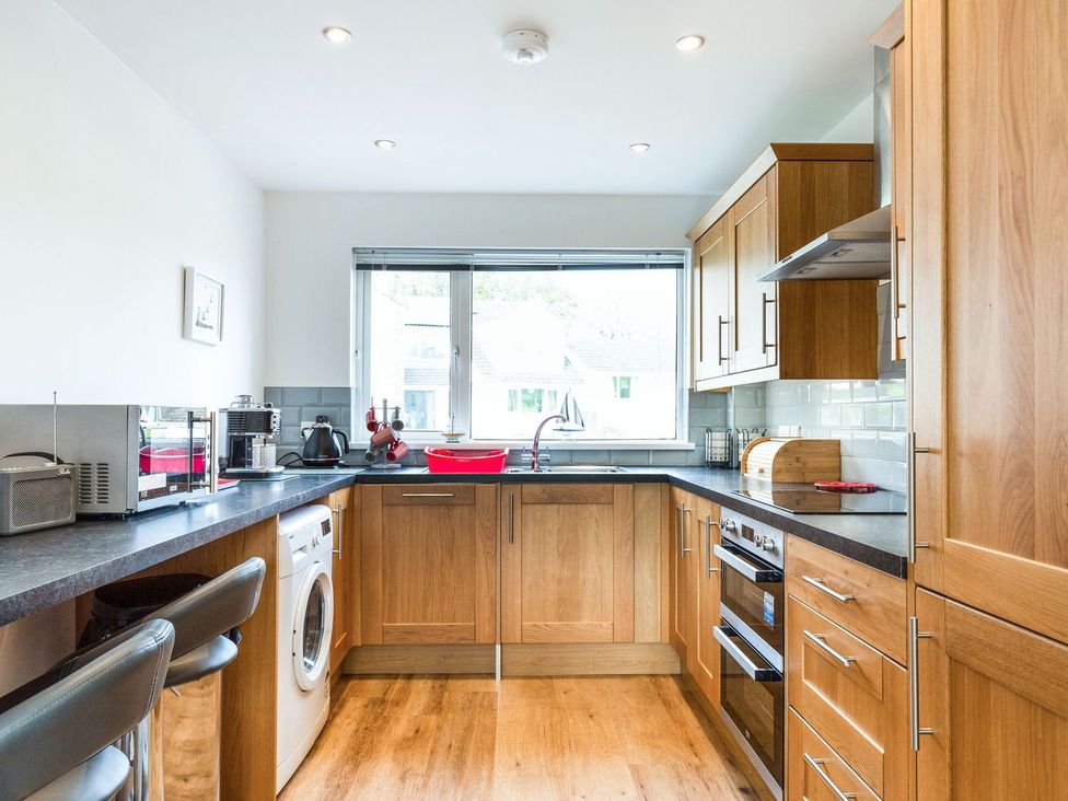A kitchen with wood cabinets and appliances at Orchard View in St. Austell