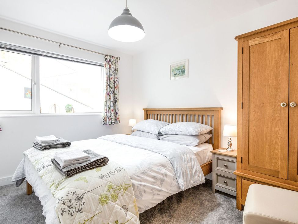 A bedroom with a bed and wardrobe at Orchard View in St. Austell