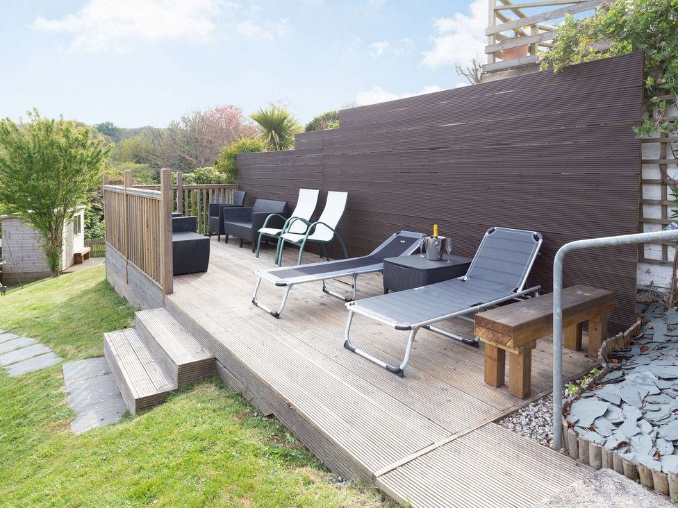 An outdoor area with lounge chairs and a table at Orchard View in St. Austell