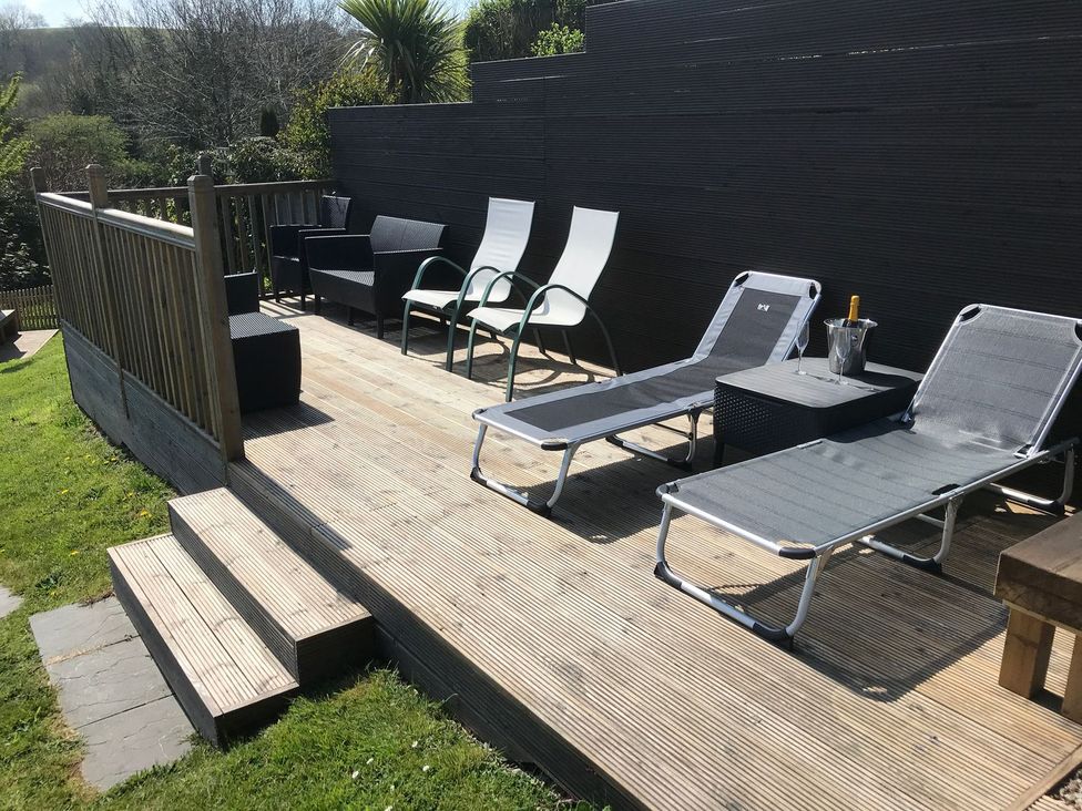 An outdoor space with lounge chairs and a coffee table at Orchard View St. Austell