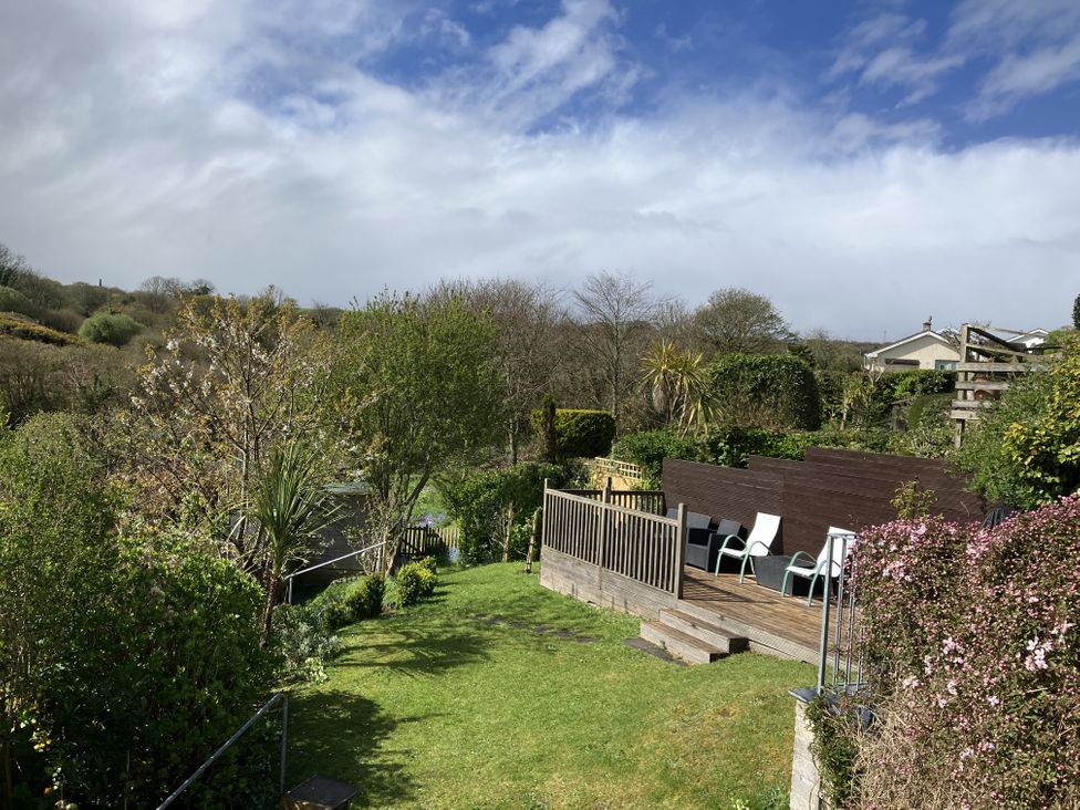 A garden with decking and chairs at Orchard View in Polgooth