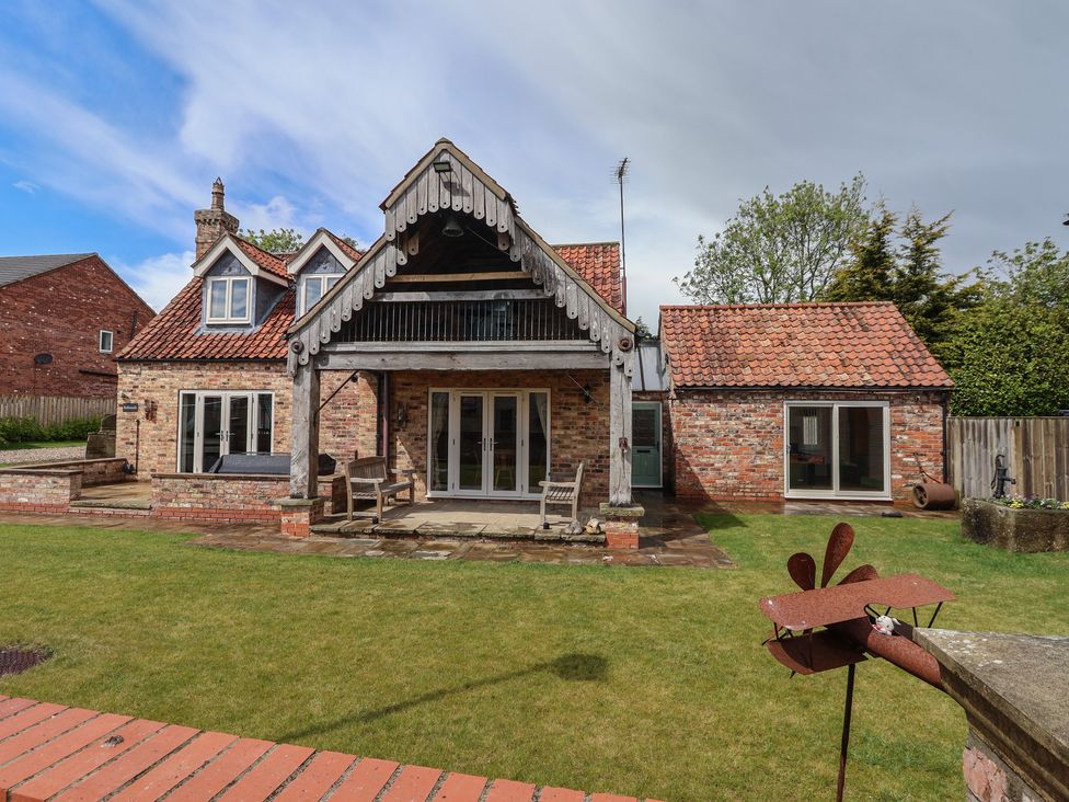 An outdoor view of a house with a patio and garden at Redwoods in Leven Near Beverley