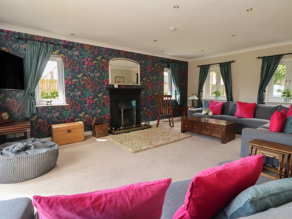 A living room with a fireplace, sofa, and television at Redwoods in Leven Near Beverley