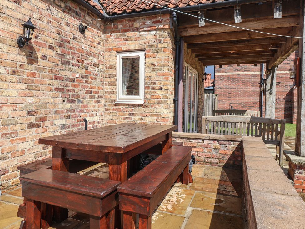 An outdoor patio area with a wooden table and benches at Redwoods Leven Near Beverley
