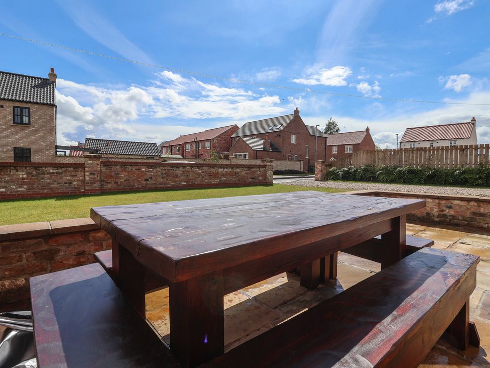 A garden with a wooden table and benches at Redwoods Leven Near Beverley