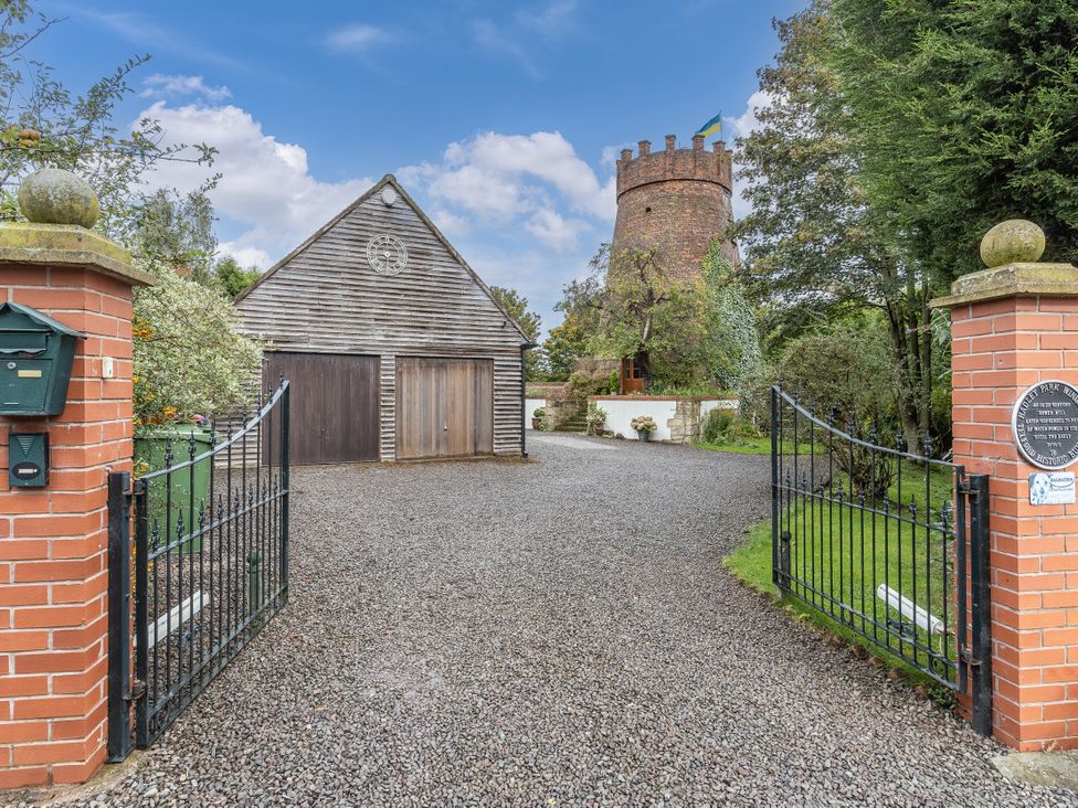 An outdoor view with a gravel driveway and a wooden barn at Hadley Park Windmill