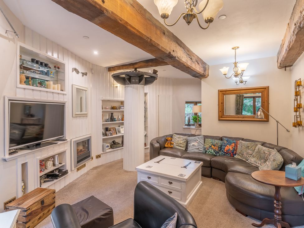 A living room with a sofa, coffee table, and television at Hadley Park Windmill 