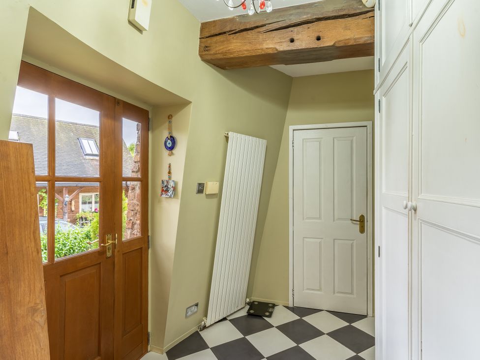 A hallway with a front door and storage cabinet at Hadley Park Windmill