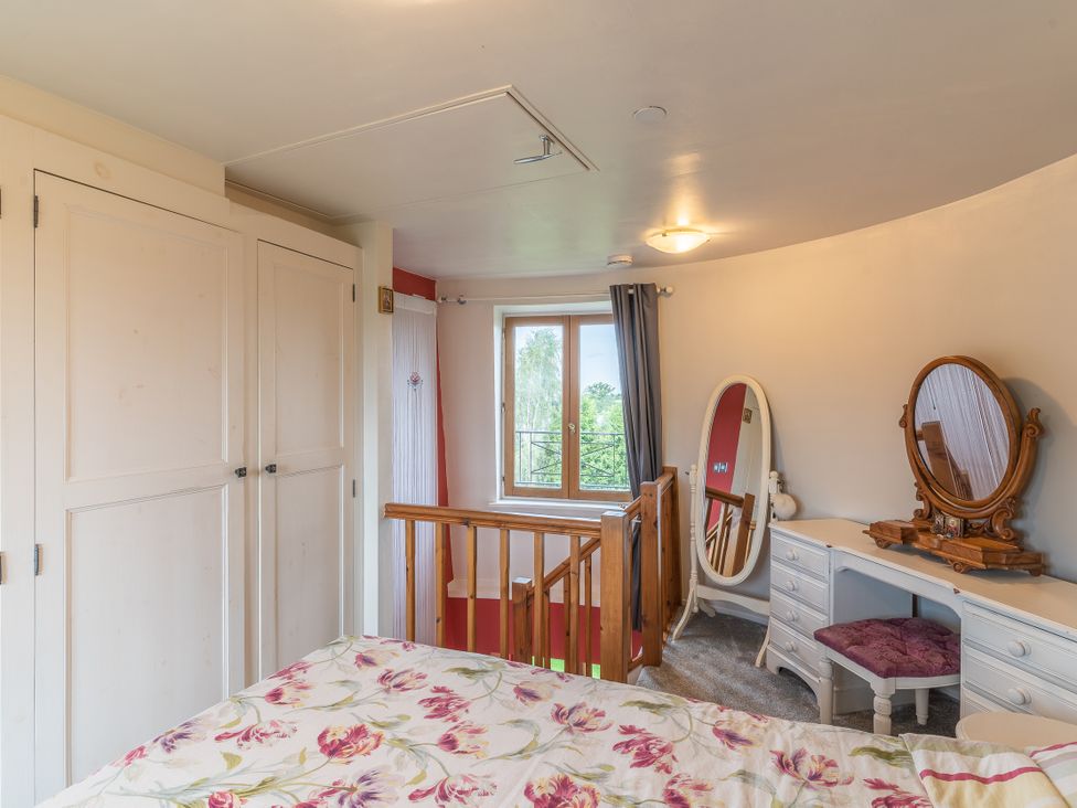 A bedroom with a bed and dressing table at Hadley Park Windmill