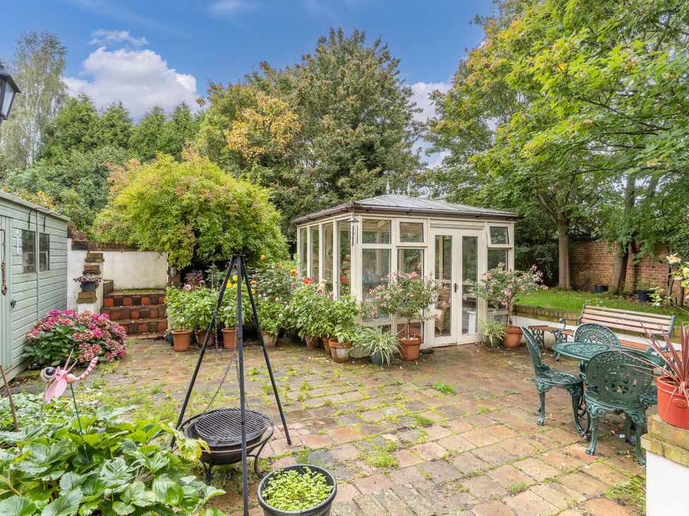 A garden with a greenhouse and seating area at Hadley Park Windmill 