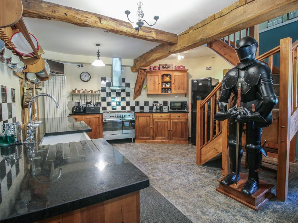 A kitchen with wooden cabinets and a knight statue at Hadley Park Windmill near Telford