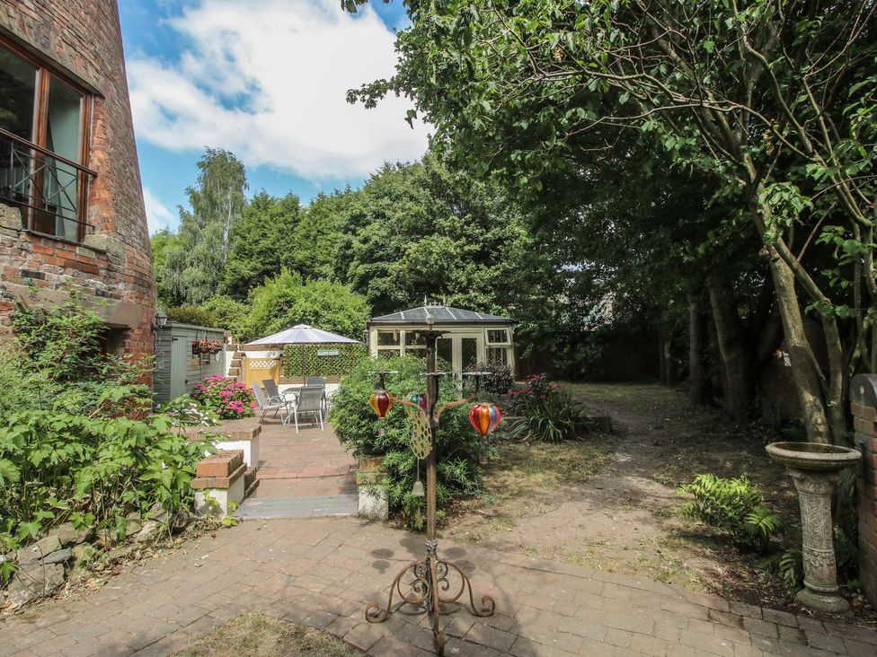 A garden with a gazebo, chairs, and a stone birdbath at Hadley Park Windmill near Telford