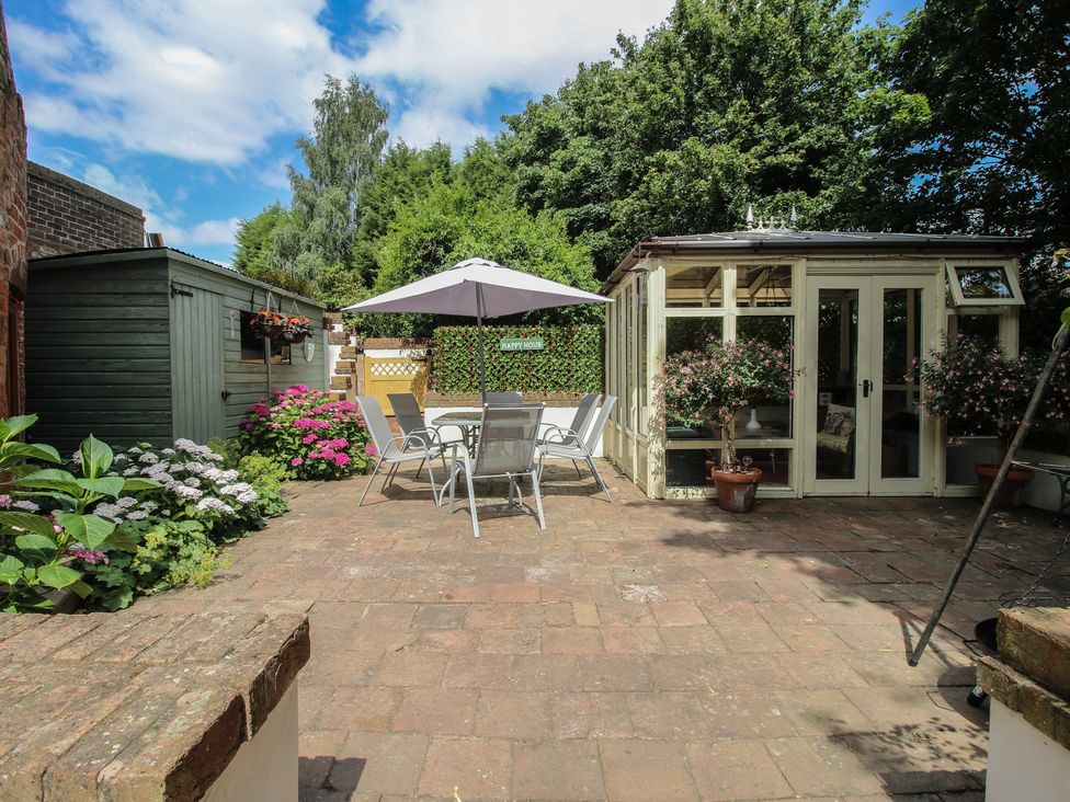 A garden with a shed, table, chairs, and plants at Hadley Park Windmill near Telford