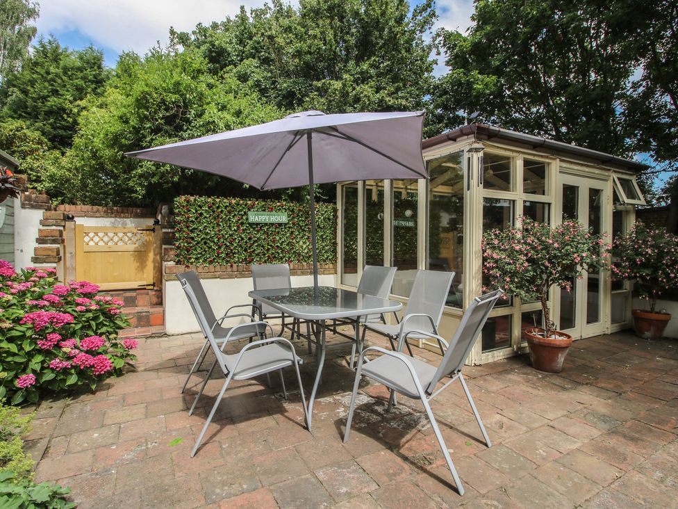 A garden with a table and chairs under an umbrella at Hadley Park Windmill near Telford