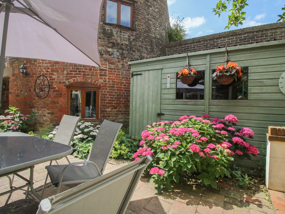 A garden with a table, chairs, flowers, and a shed at Hadley Park Windmill near Telford
