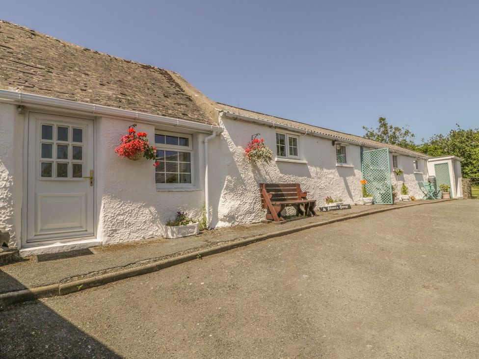 An exterior view of a cottage with a bench and planters at Falconers Cottage