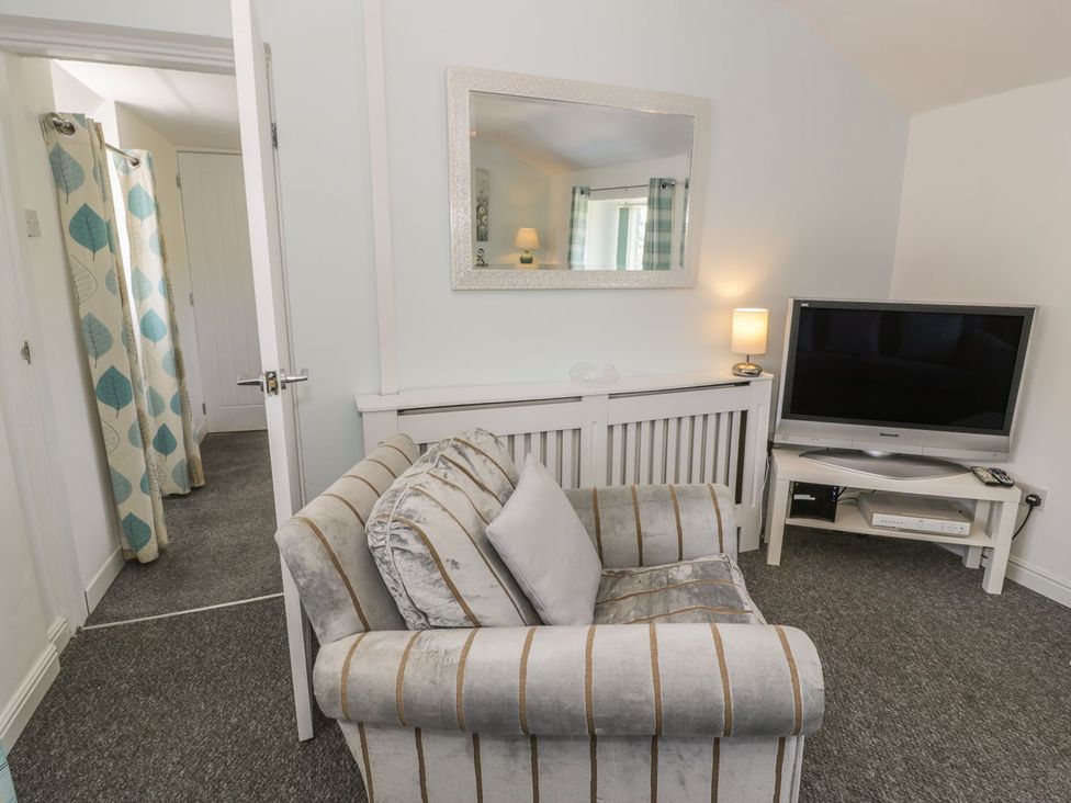 A living room with an armchair and television at Falconers Cottage