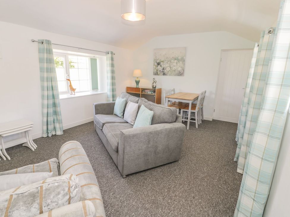 A living room with a sofa, table and chairs at Falconers Cottage