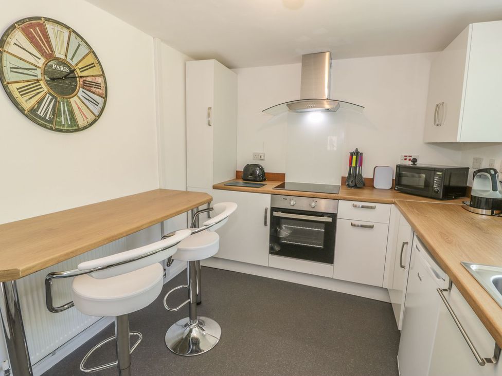 A kitchen with bar stools and appliances at Falconers Cottage