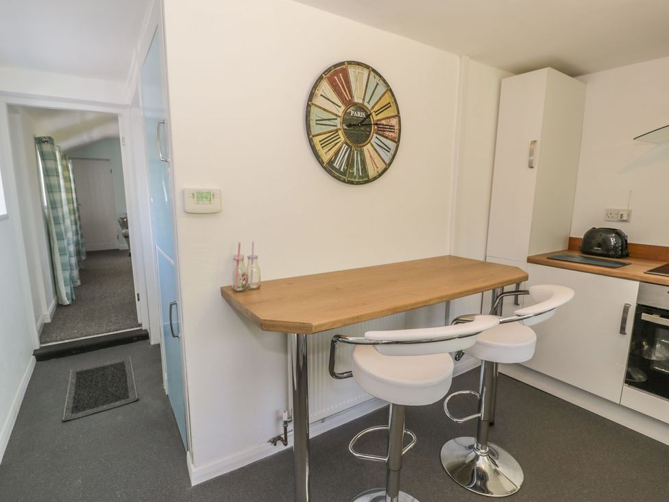 A kitchen with bar stools and a counter at Falconers Cottage
