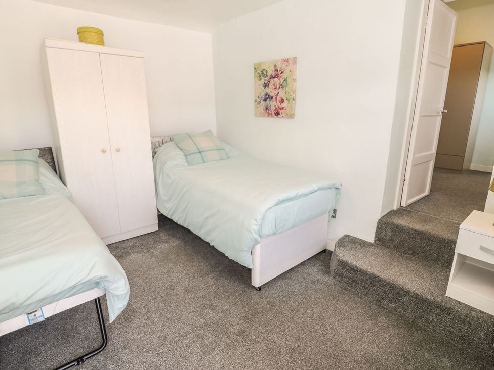 A bedroom with two beds and a wardrobe at Falconers Cottage