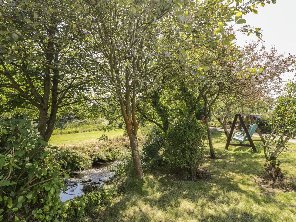 A garden with trees and a stream at Falconers Cottage