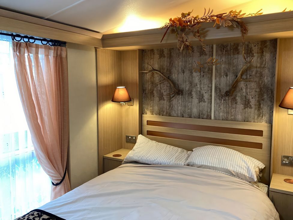 A bedroom with a bed and lamps at Beachside in Towyn