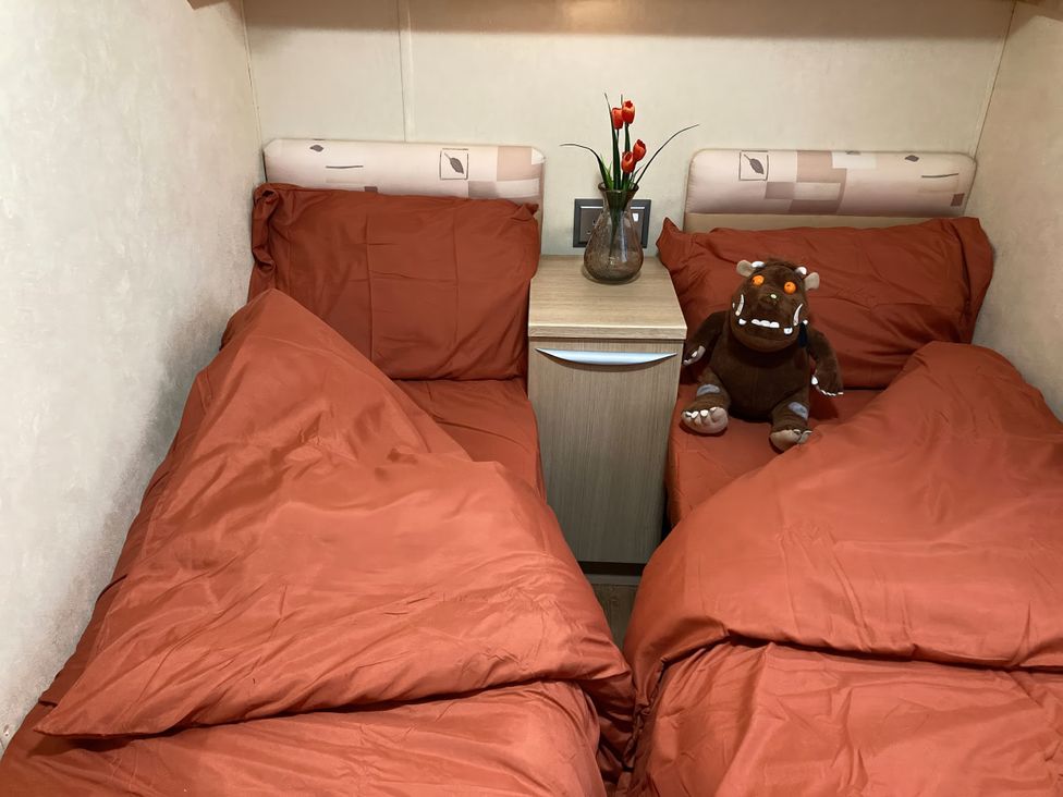 A bedroom with two beds and a bedside table at Beachside in Towyn